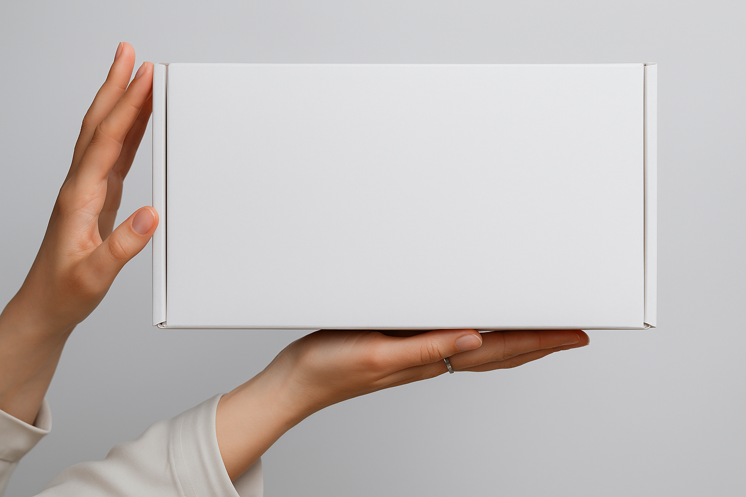 Person holding a white rectangular box against a plain background